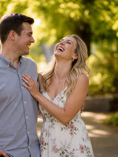 Couple laughing walking in park, floral sundress, golden hour, candid engagement photos